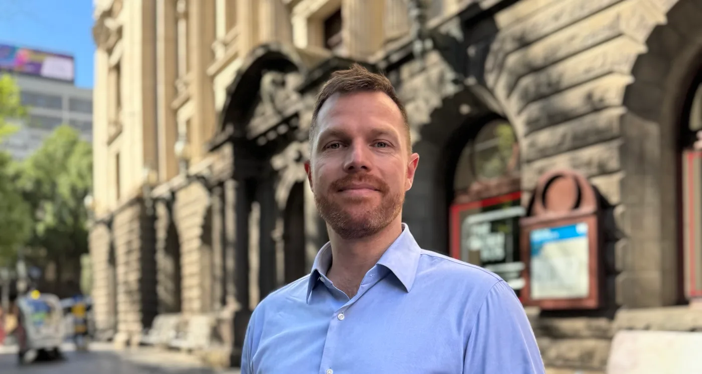 Cr Andrew Rowse standing on a city street in front of a historic stone building